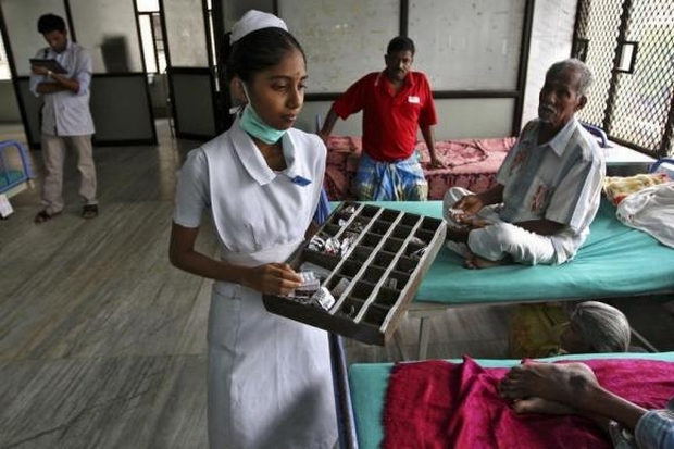 A paramedic distributes free medicine provided by the government to patients inside a ward at RGGGH in Chennai